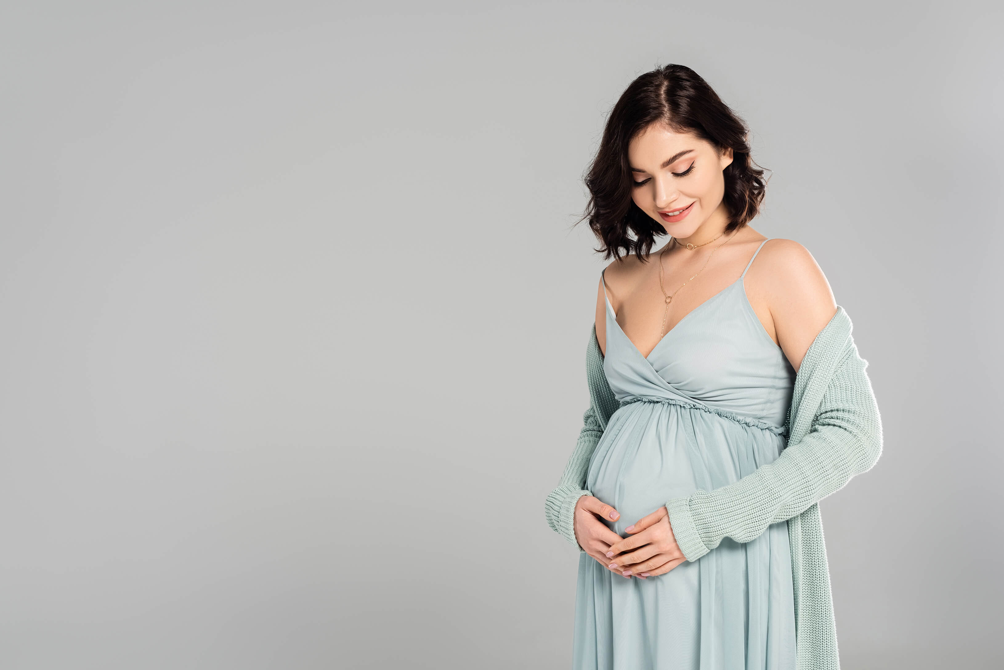 Eine Schwangere in einem hellblauen Abendkleid, Umstandsmode, Schwangerschaftsmode