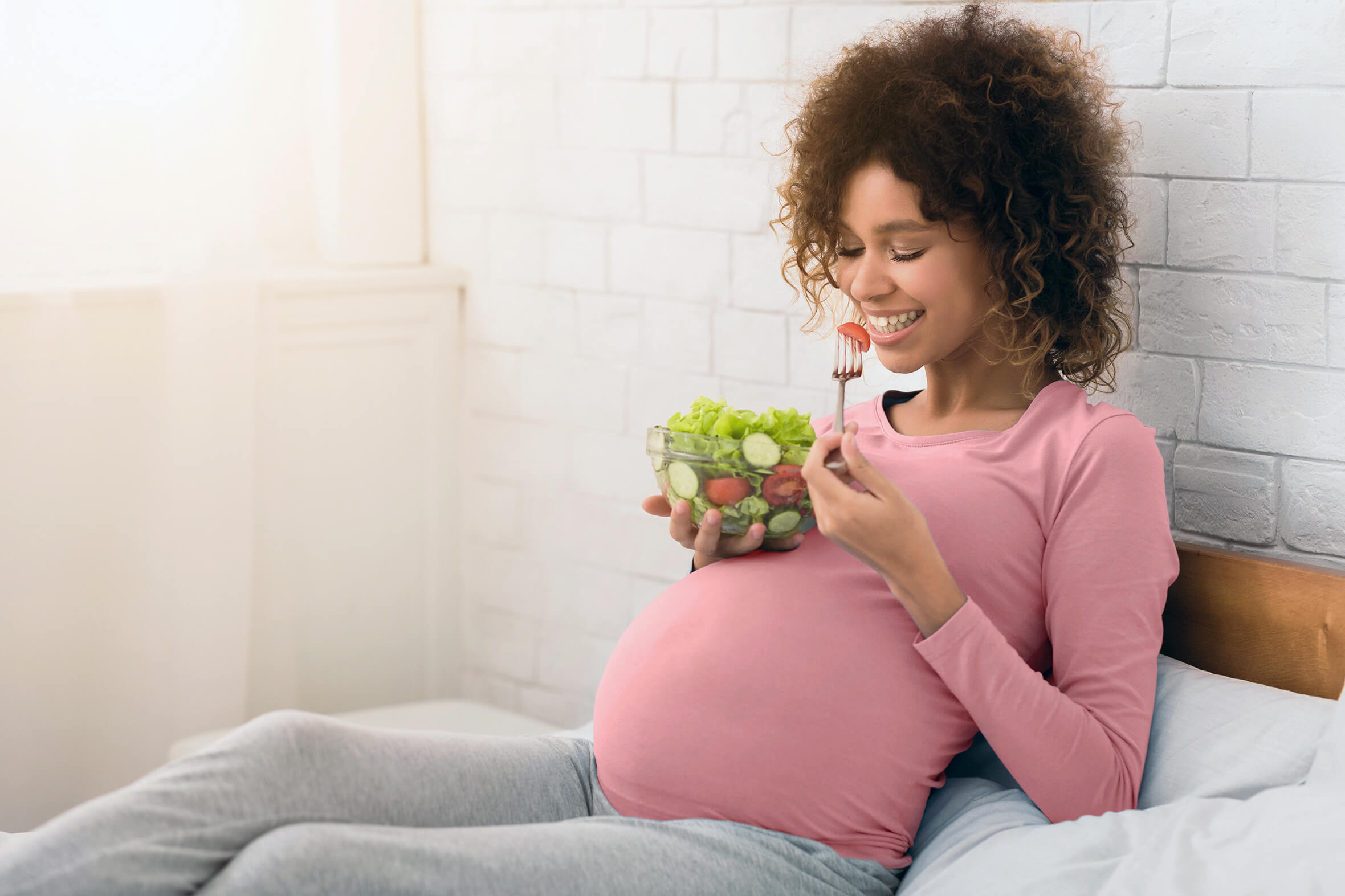 Eine Schwangere isst Salat, um ihr Immunsystem in der Schwangerschaft zu stärken