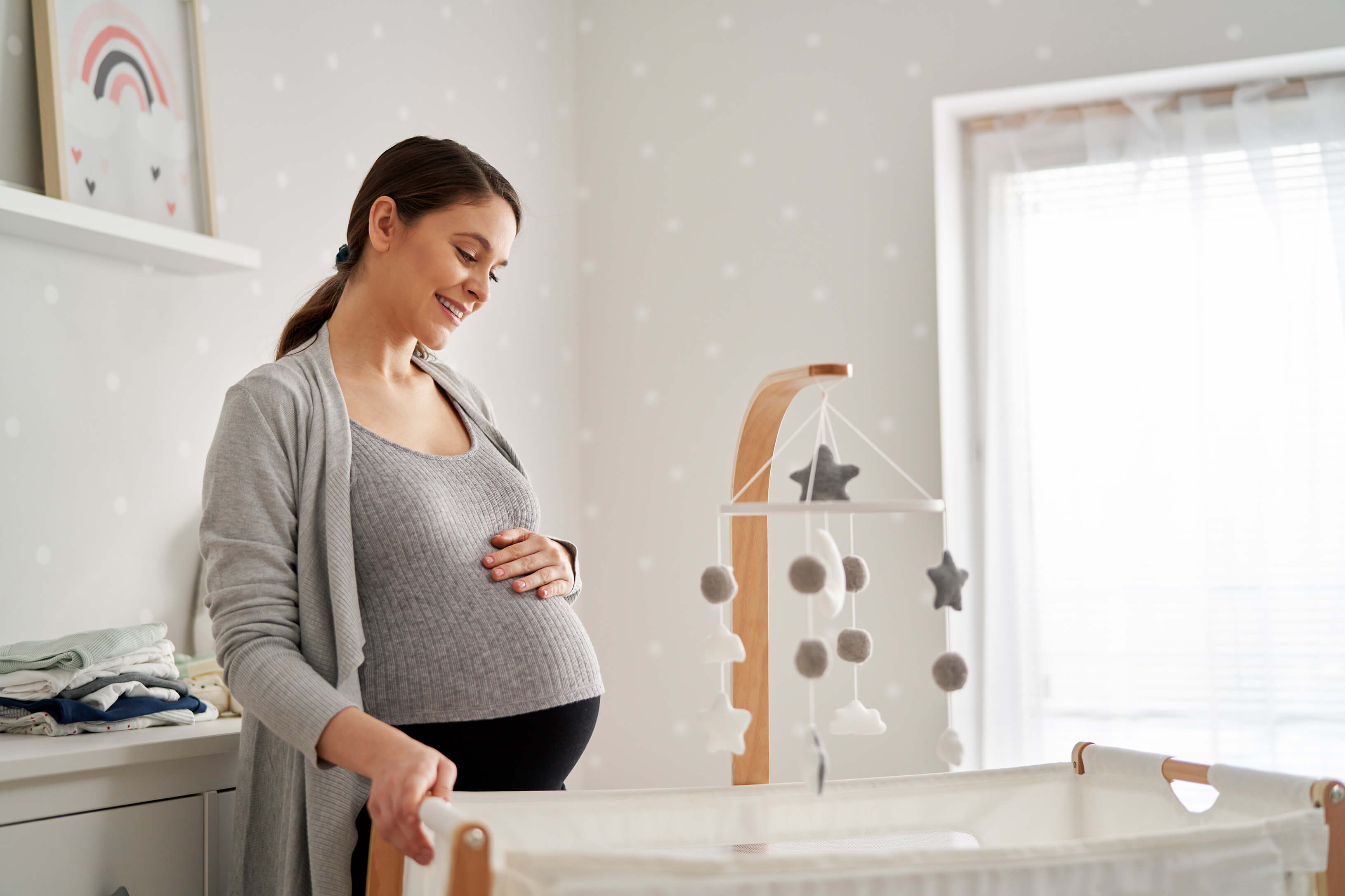 Schwangere im Kinderzimmer vorm Babybett