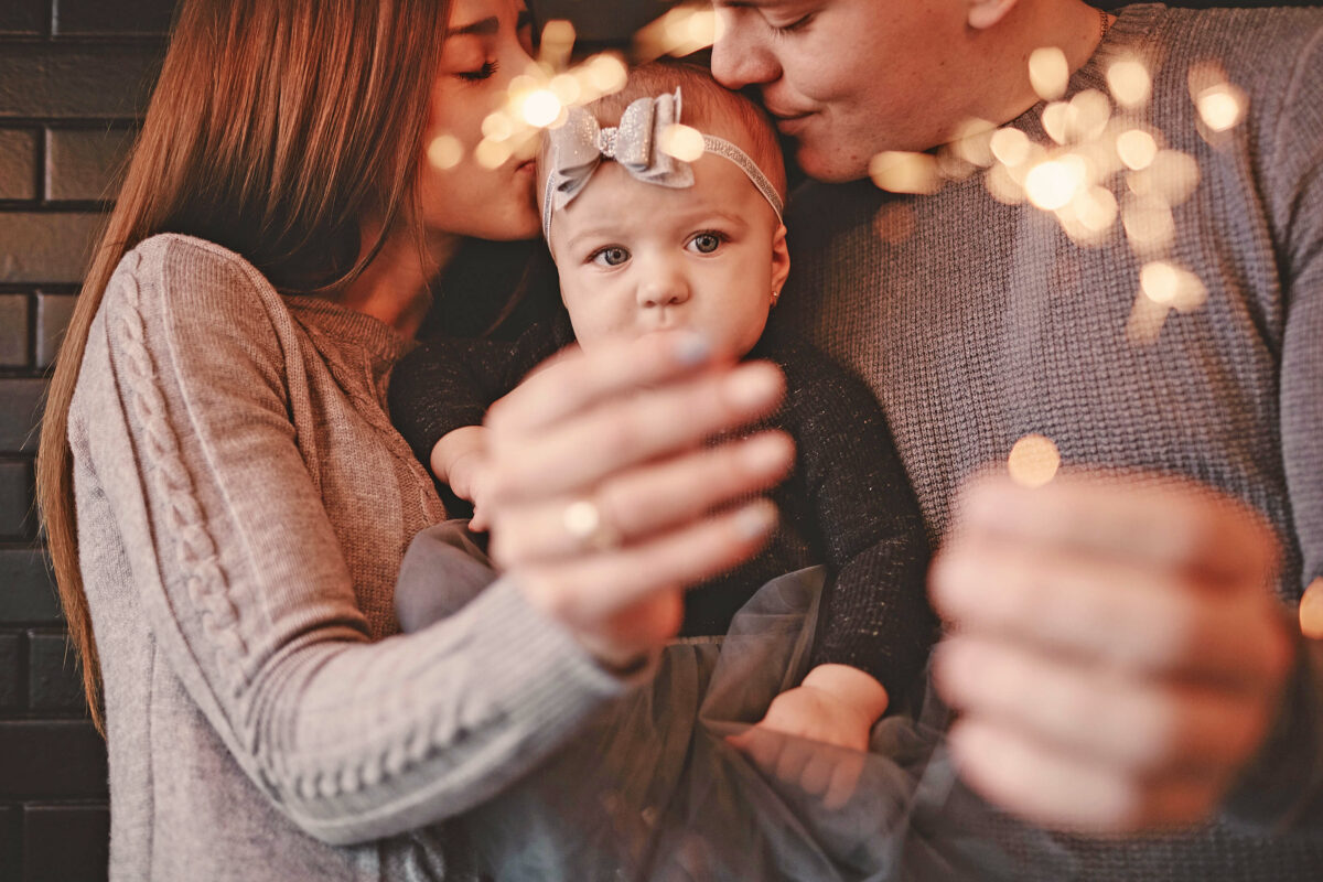 Mutter und Vater mit Baby an Silvester, Wunderkerzen